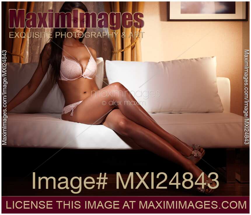 Beautiful sexy black woman in lingerie sitting on sofa