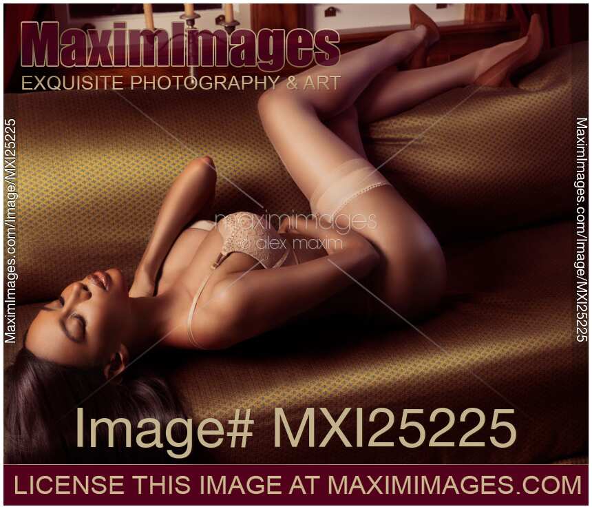 Beautiful sexy black woman with in beige lingerie and stockings lying on sofa in sensual pose