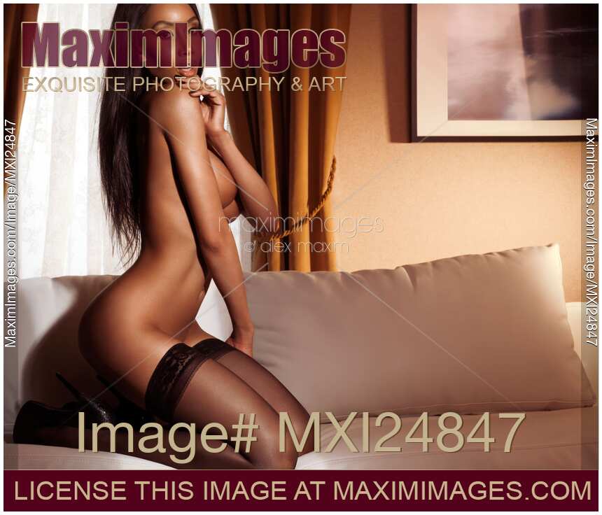 Beautiful sexy half naked woman in black stockings posing on sofa