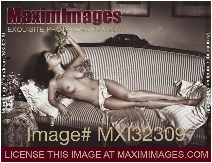 Beautiful sexy nude woman lying on a couch naked with grapes in her hand French boudoir Black and white portrait