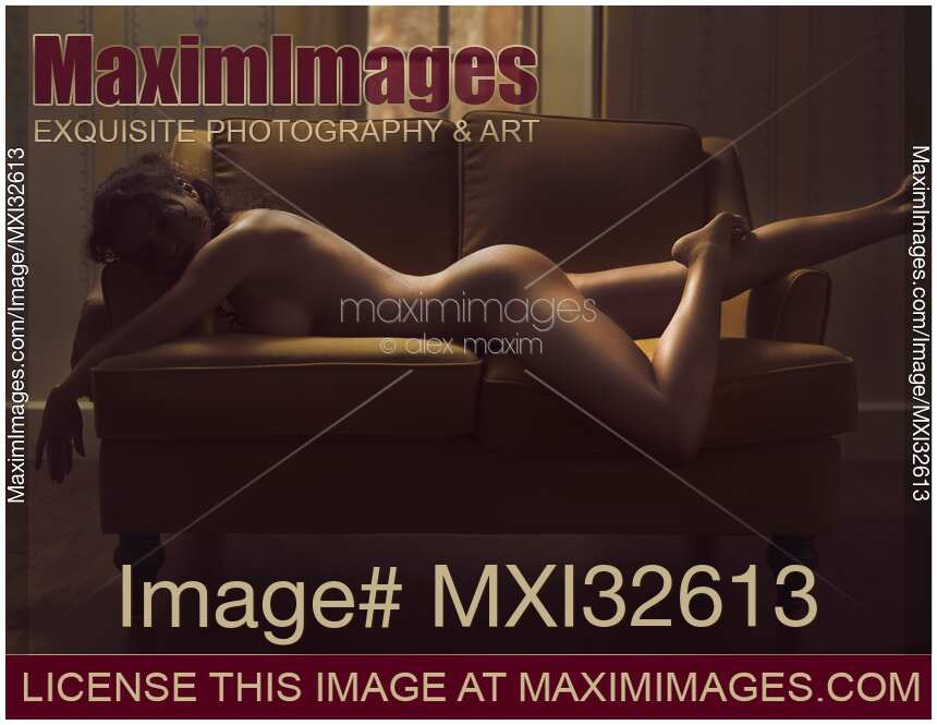 Beautiful sexy outline of a nude woman curvy body on a couch naked in dim shadowy gold light