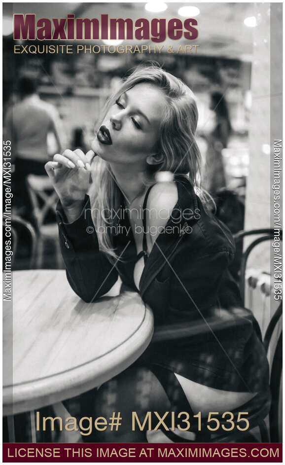Beautiful sexy provocatively dressed woman in stockings sitting at a restaurant table