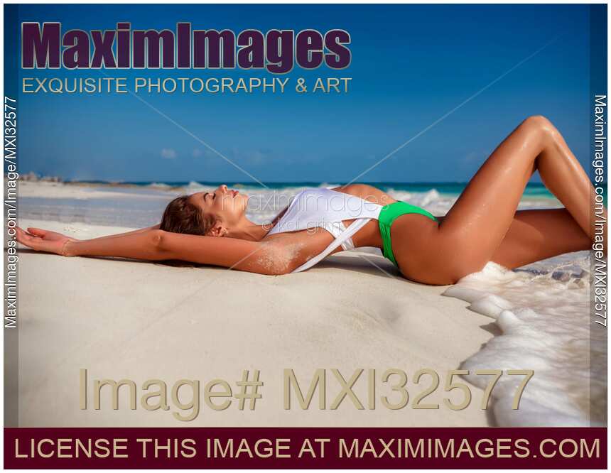 Beautiful sexy sun tanned woman in fashion swimsuit lying on white sandy shore of Caribbean Sea beach in Cancun Mexico
