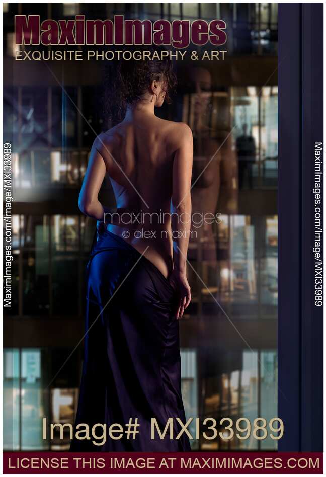 Beautiful sexy woman in undressing in front of a window with a man watching her seductive dance