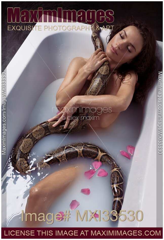 Beautiful sexy woman taking a bath holding a large boa snake against her naked wet body
