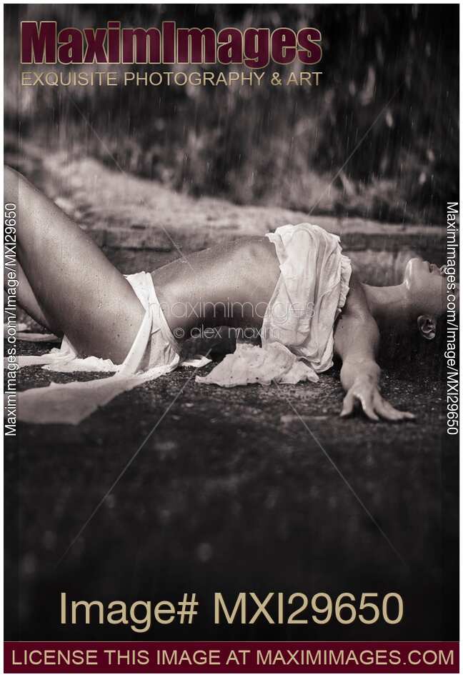 Beautiful sexy young woman in beach wear lying on the ground under pouring rain