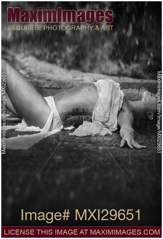 Beautiful sexy young woman in beach wear lying under pouring rain Black and white