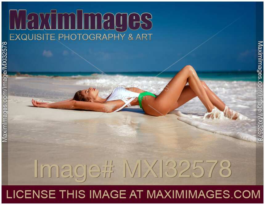Beautiful sexy young woman in one-piece fashion swimsuit lying on sandy shore of ocean beach in Cancun Mexico