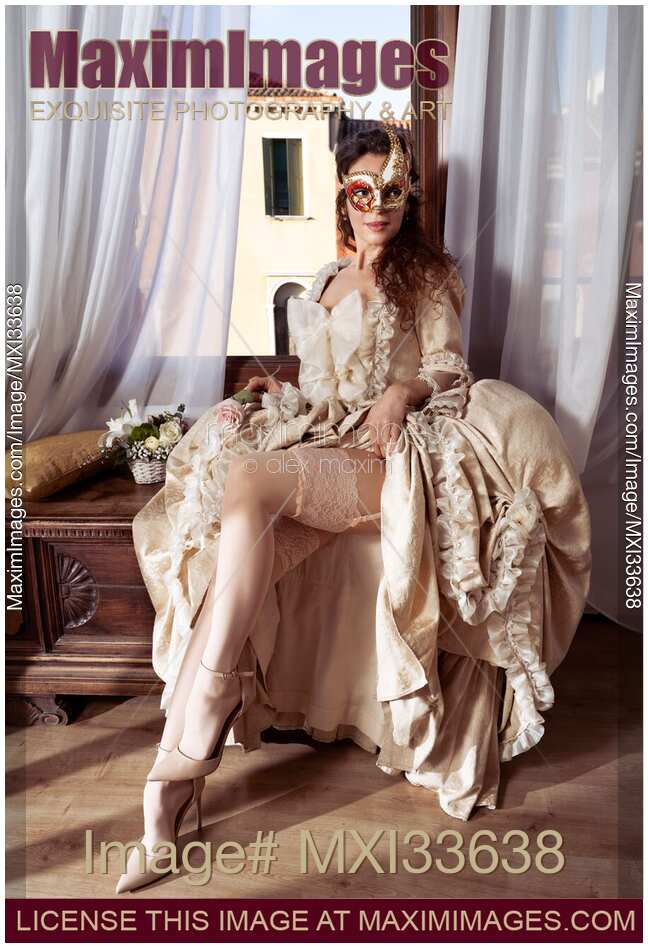 Beautiful Venetian lady courtesan in a carnival mask flirting by raising her vintage dress revealing sexy legs in stockings
