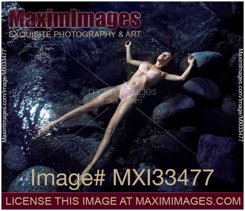 Beautiful woman in pink lingerie lying relaxed half-naked in calm clear water of a river. View from above.