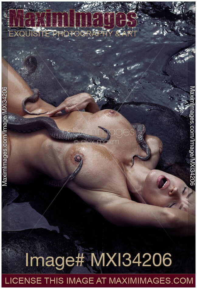 Beautiful woman making love to a giant octopus lying on sea shore with tentacles caressing her sensual nude body