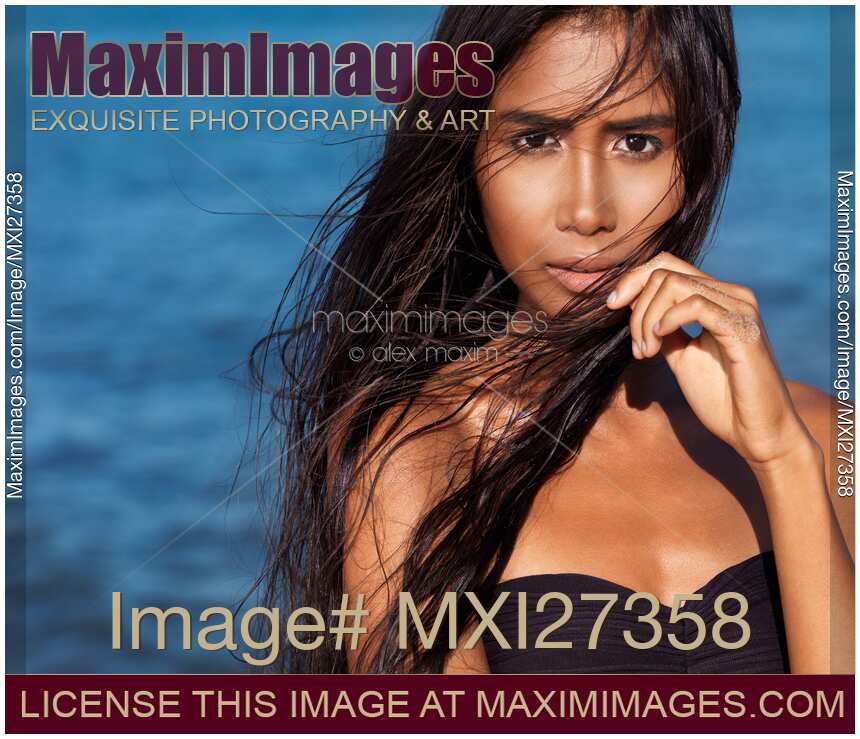 Beautiful woman portrait with long wet dark hair against blue sea water