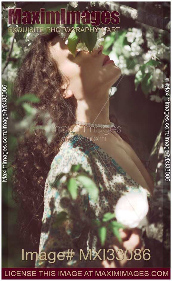 Beautiful woman profile of her face with closed eyes in cherry tree blossom white flowers