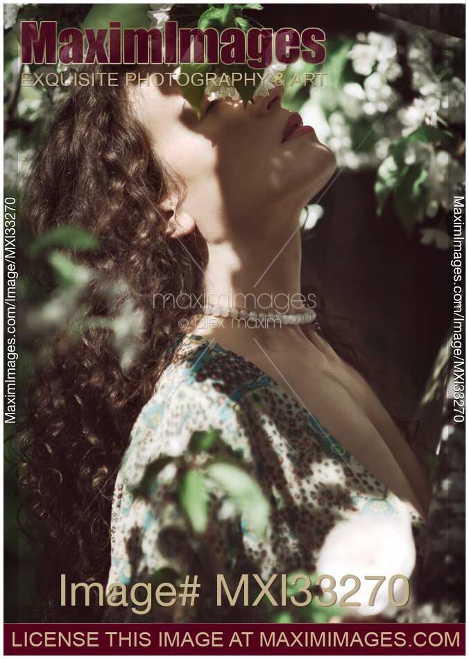 Beautiful woman profile of her face with closed eyes in cherry tree blossom white flowers