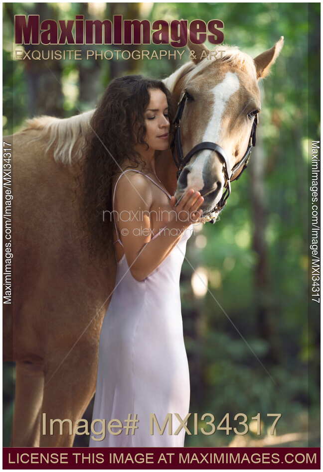 Beautiful woman rider in elegant dress caressing a horse in nature with tender relaxed expression