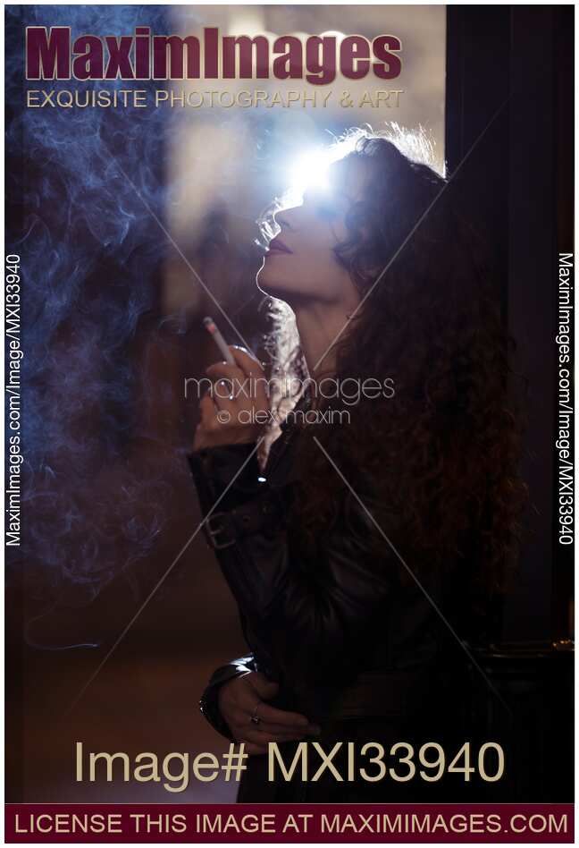 Beautiful woman smoking a cigarette standing on a night city street