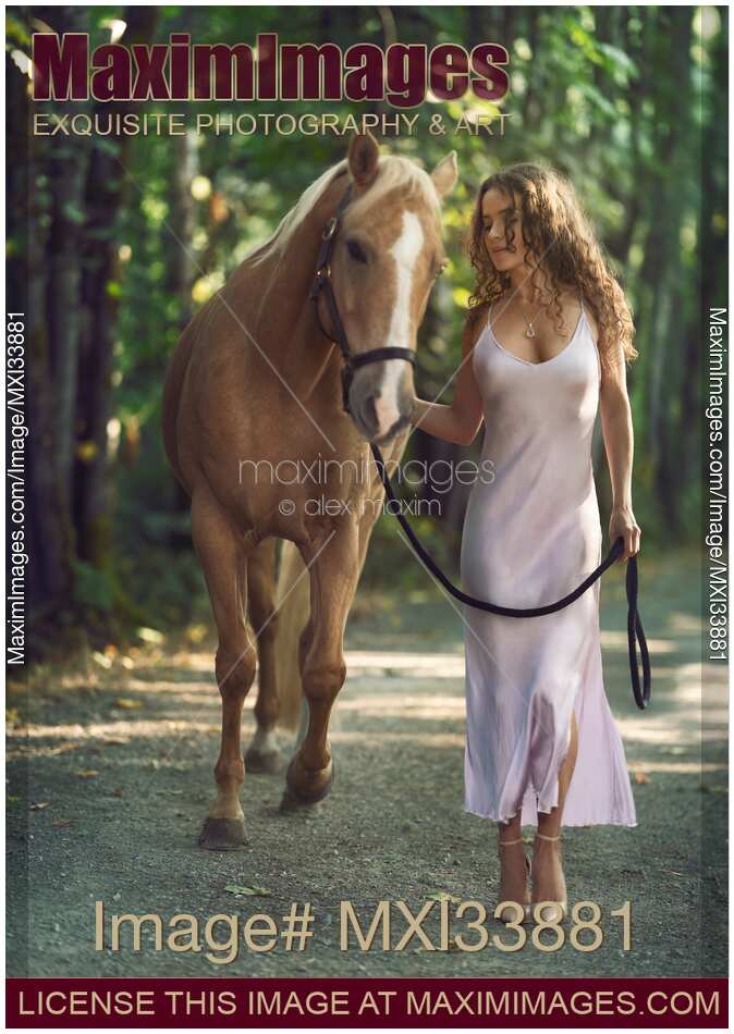 Beautiful woman walking with a horse along the trail in an elegant silk dress