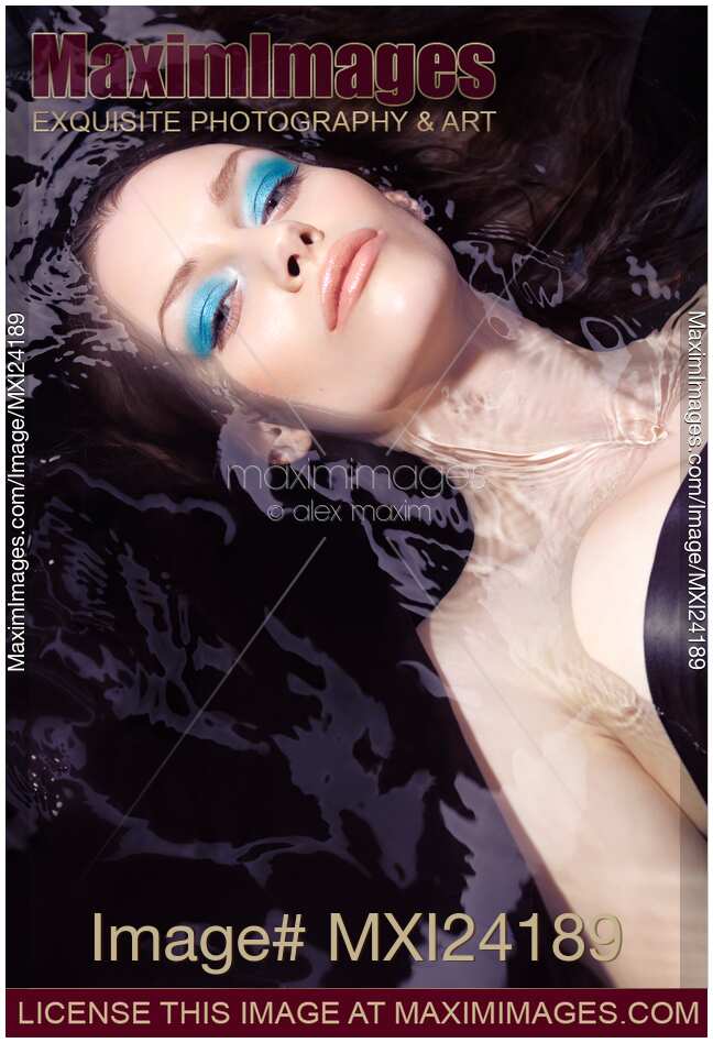 Beautiful woman with blue makeup lying in water