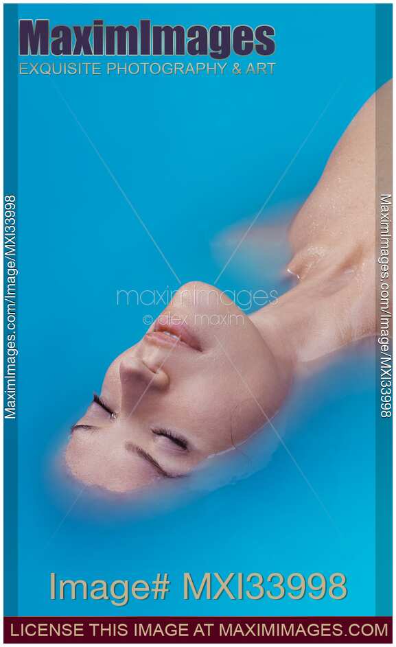 Beautiful young woman face lying half submerged in turquoise blue water abstract beauty portrait