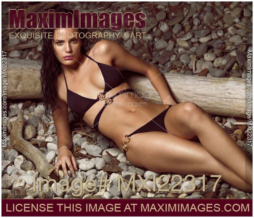 Beautiful Young Woman in Black Bikini on a Pebble Beach