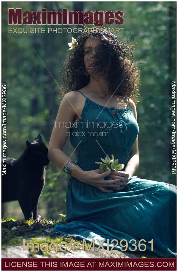 Beautiful young woman sitting in the nature wit ha black cat by her side