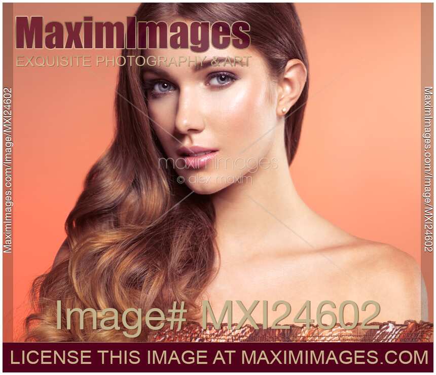 Beauty face portrait of a young woman with natural look on long wavy silky brown hair