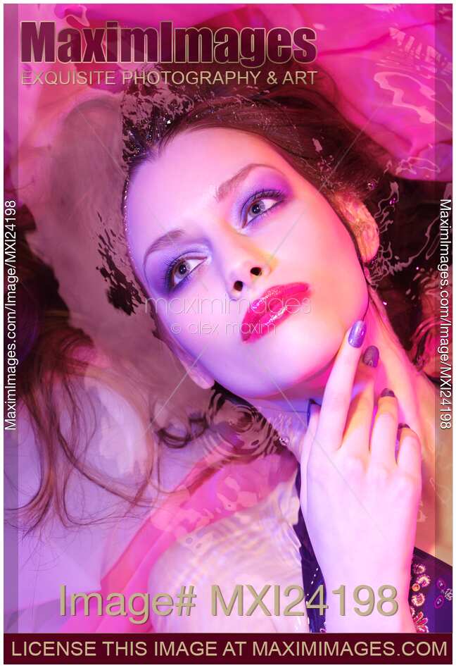 Beauty face portrait of woman lying in water with colorful makeup
