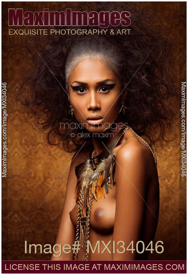 Beauty portrait of exotic asian woman with feathers and tribal accessories over her naked body