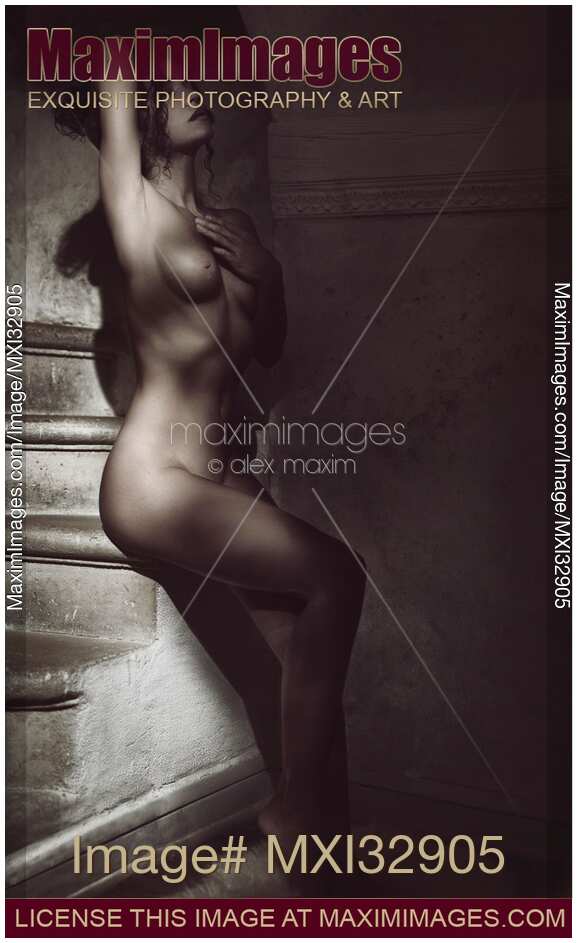 Black and white art nude portrait of a beautiful woman sitting naked on stairs of a dark old European house at night