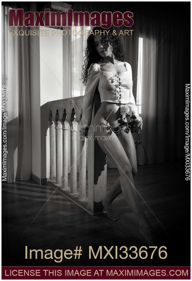 Black and white art nude portrait of a beautiful young woman dancing half-naked with a rose in dark room