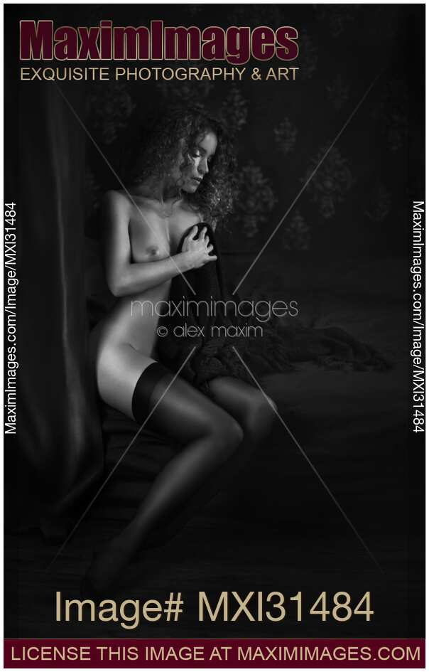 Black and white art nude Woman in stockings sitting naked on bed covering her breast with a blanket