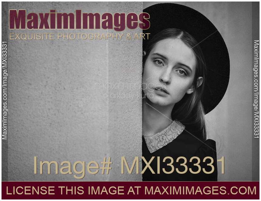 Black and white portrait of a girl with an expressive look on her face wearing a black hat
