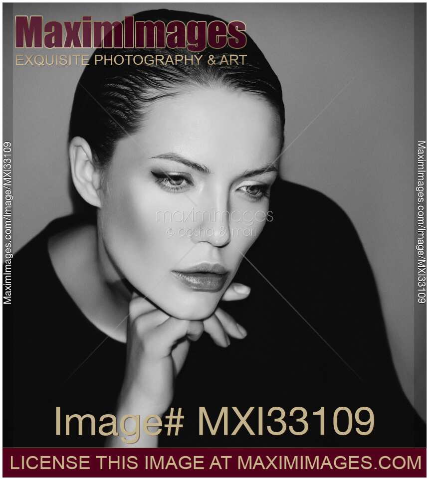 Black and white portrait of a stylish luxurious woman with a pensive sleek look leaning her head on her hand