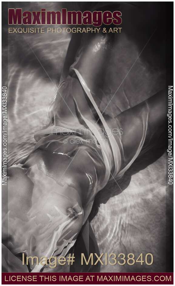 Black and white sensual nude woman body wrapped with wet sheer cloth in glossy water revealing her breasts and parted legs