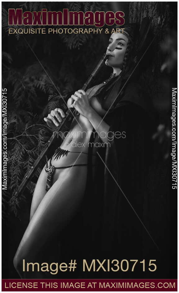 Black and white sensual portrait of a sexy Native American tribal woman playing bamboo flute in the nature