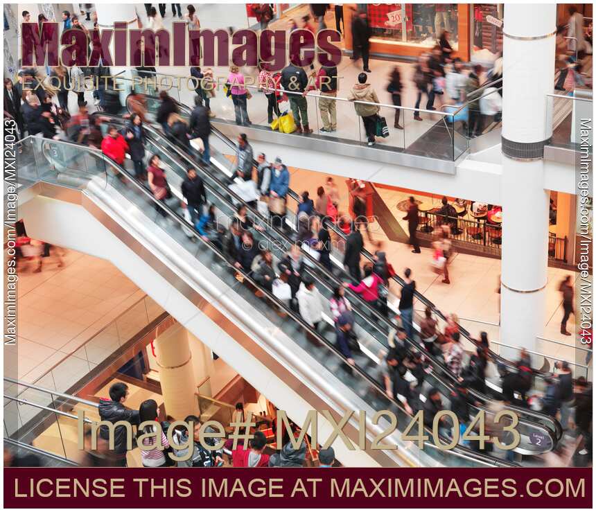 Blurred with motion people on escalator in shopping mall
