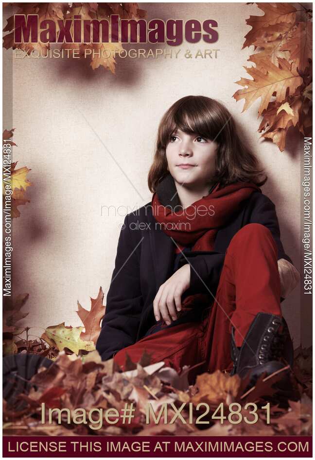 Boy sitting on autumn leaves artistic portrait