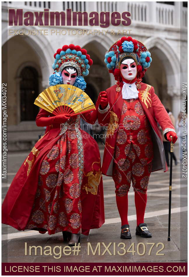 Brightly dressed couple in oriental red costumes and masks during the Carnival of Venice Italy