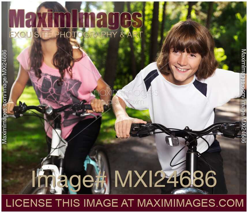 Brother and sister riding bikes in park