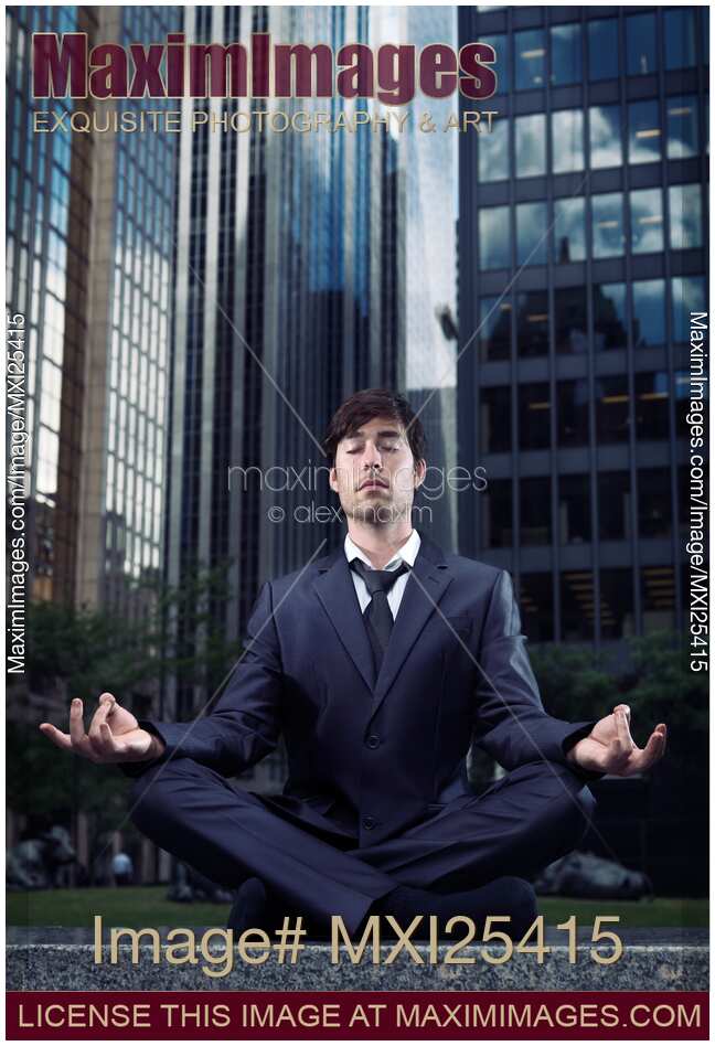 Businessman meditating with office buildings behind him