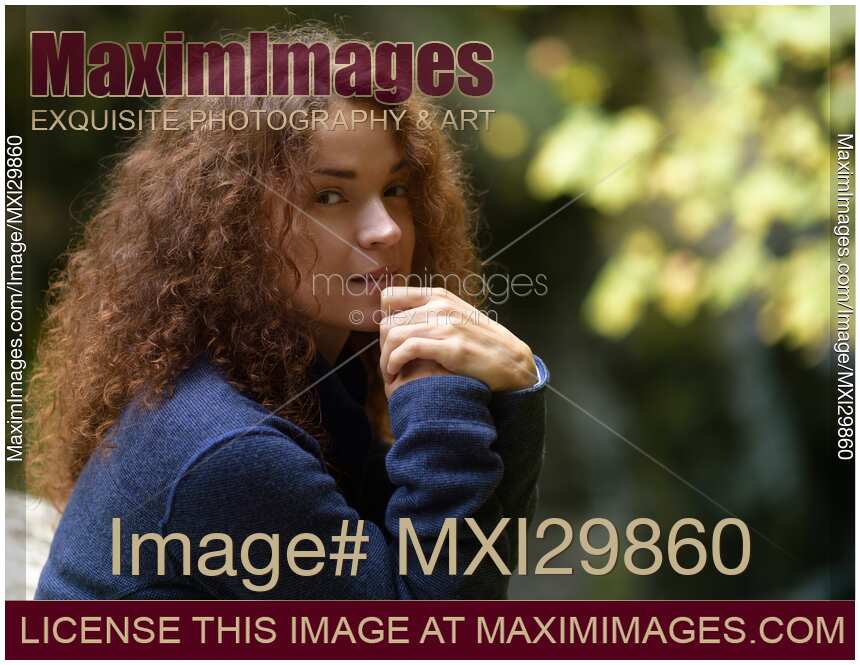 Candid natural portrait of young woman with tranquil thoughtul expression in the nature
