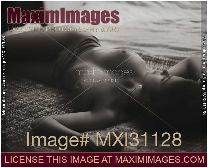 Candid nude portrait of a beautiful young naked woman lying relaxed in soft dim night light