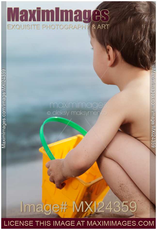 Child playing at the beach sitting by the water