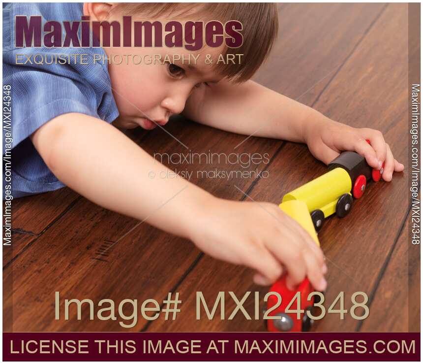 Child playing with a toy train on the floor