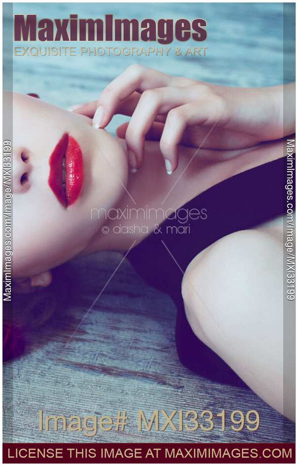 Closeup of a beautiful woman sensual face with bright red lipstick lying on blue wooden floor