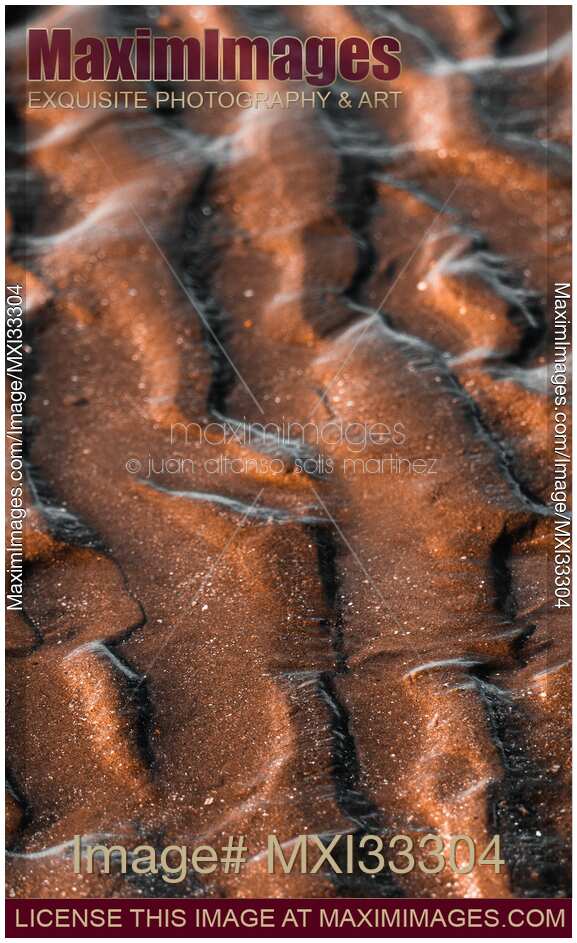 Closeup of a wave patterns background in the sea sand at low tide at sunrise