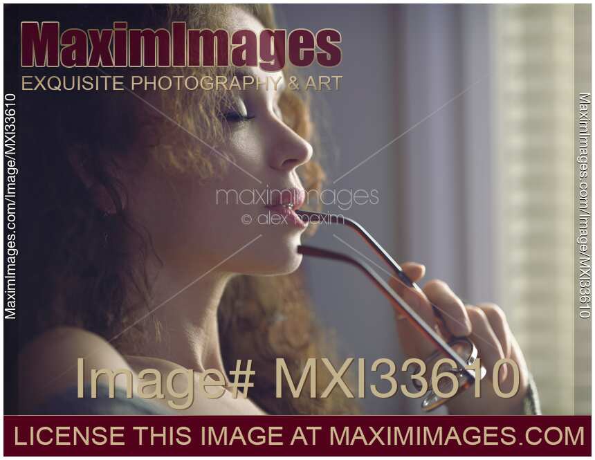 Closeup of a woman face with closeup eyes with reading glasses touching her sensual lips