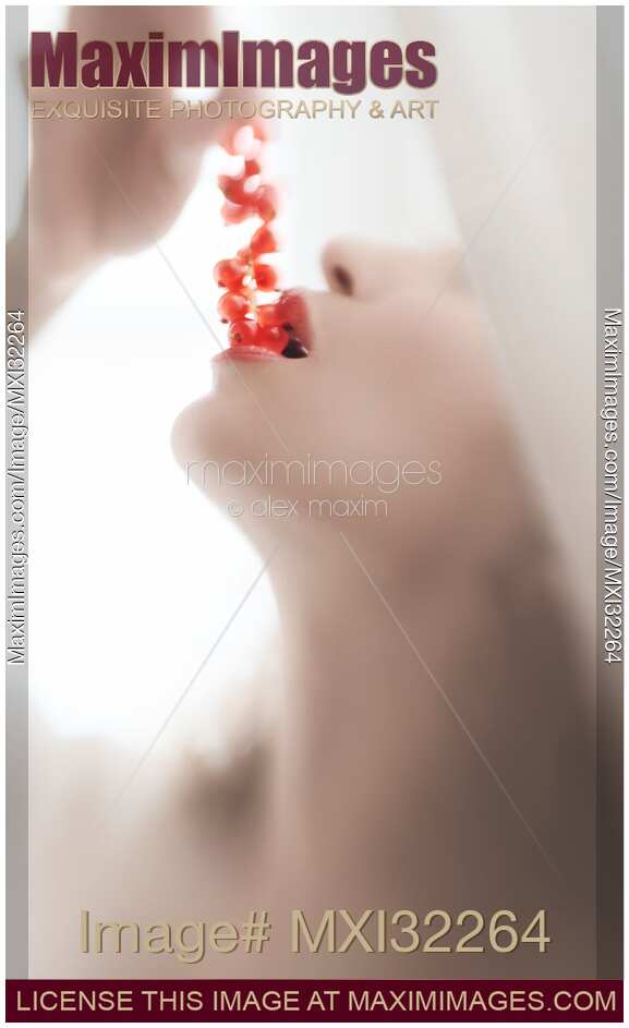 Closeup of a woman sensual mouth with open lips eating red currants