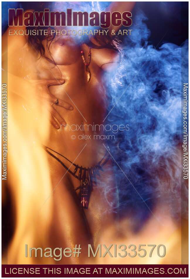 Closeup of beautiful nude body of a native woman dancing naked at night surrounded by fire flames and smoke