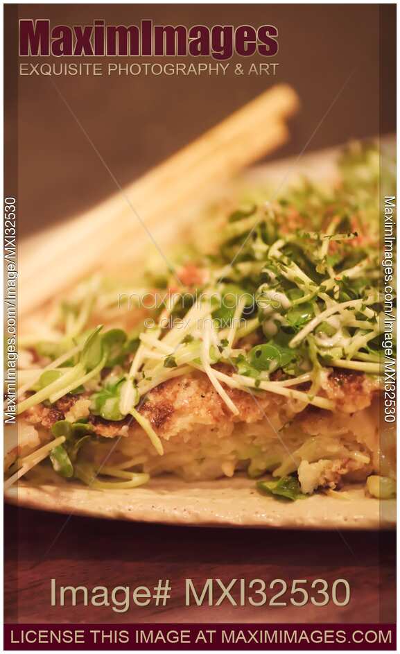 Closeup of Okonomiyaki Japanese dish on a plate cabbage pancake with sprouts topping in Japan